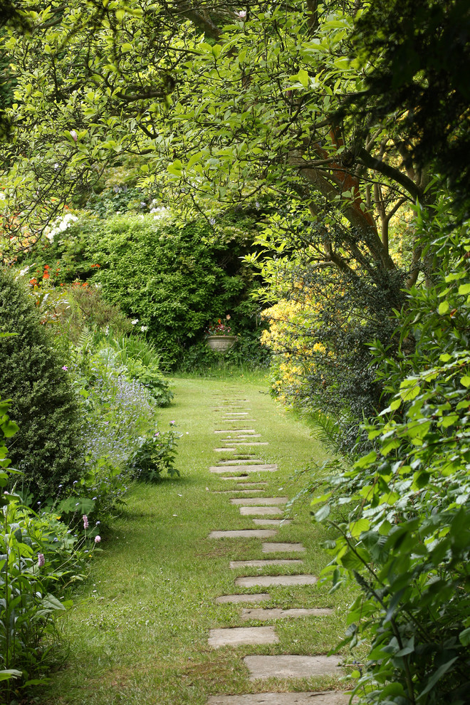 Réalisation d'un grand aménagement d'entrée ou allée de jardin arrière tradition avec une exposition partiellement ombragée et des pavés en pierre naturelle.