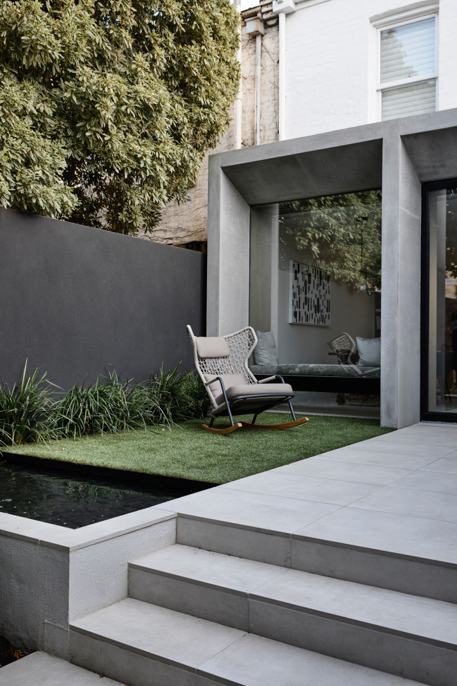 Contemporary back formal partial sun garden in Melbourne with a water feature.