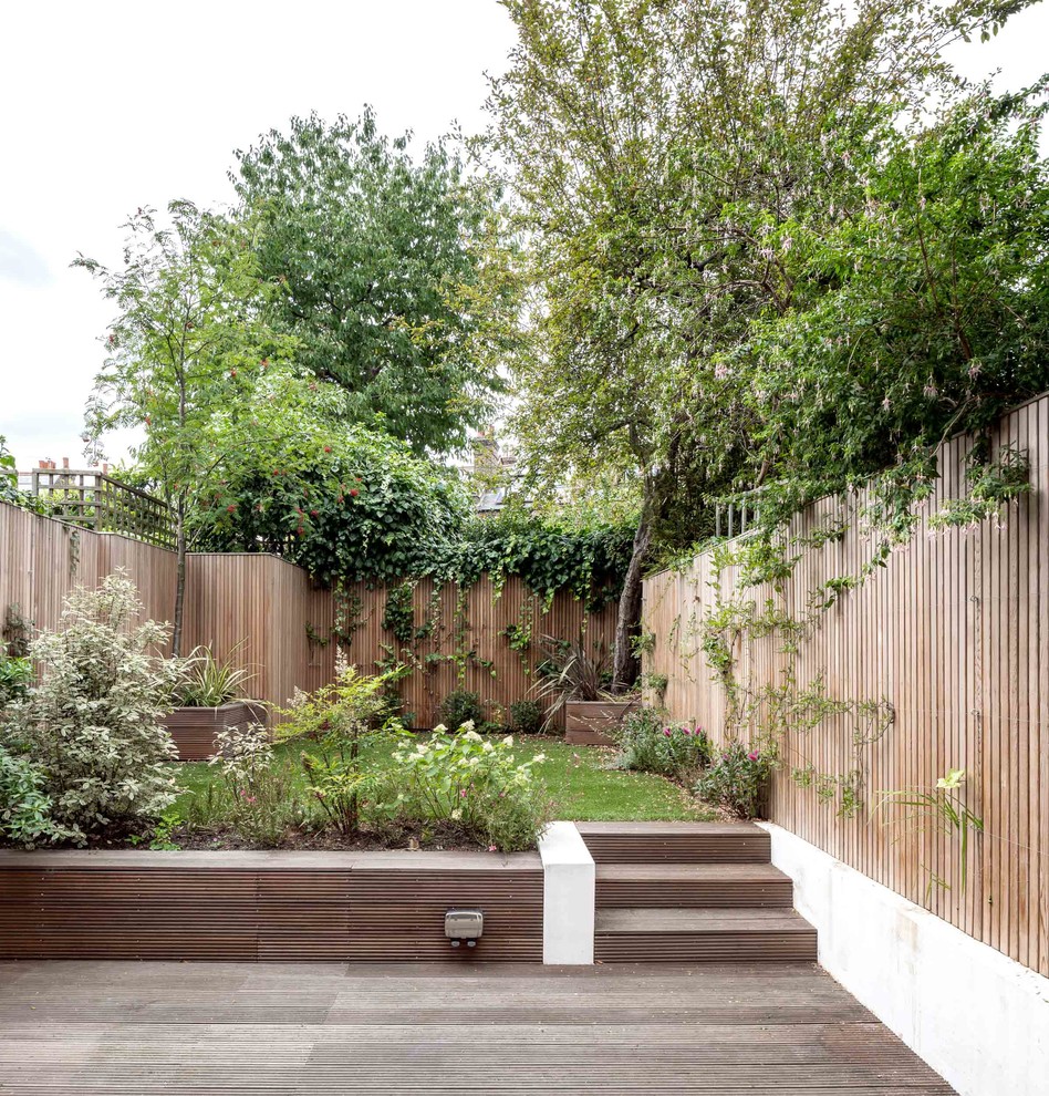 Inspiration for a mid-sized contemporary backyard retaining wall landscape in London with decking.