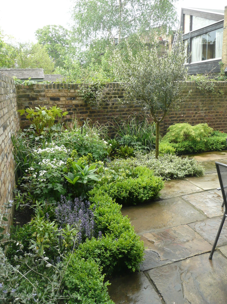 Diseño de jardín tradicional pequeño en primavera en patio trasero con jardín francés, exposición parcial al sol y adoquines de piedra natural