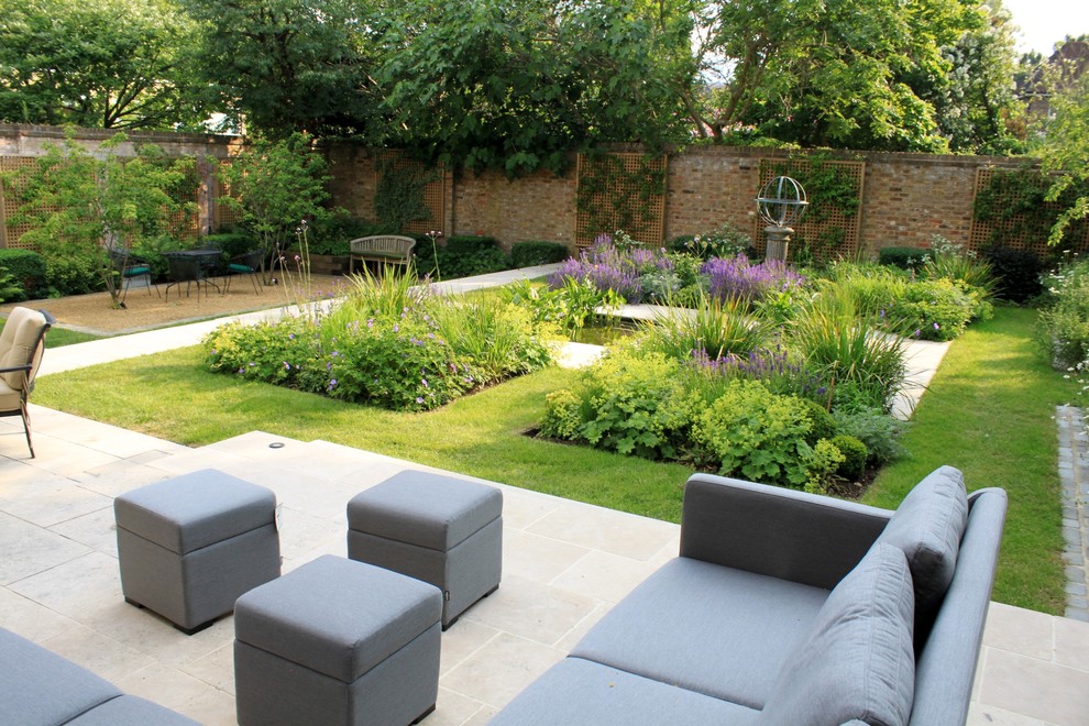 This is an example of a large contemporary back garden in London with a pond and natural stone paving.