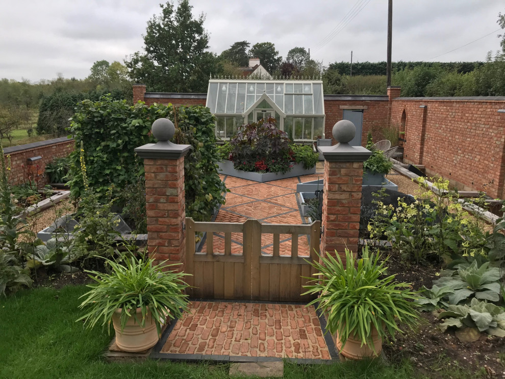 Foto de jardín clásico de tamaño medio en patio trasero con jardín francés y adoquines de ladrillo
