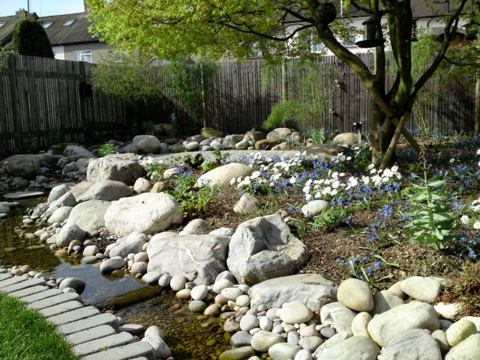 Inspiration för en stor funkis bakgård i delvis sol på våren, med en fontän och naturstensplattor