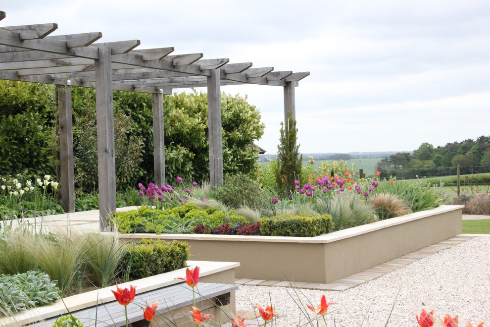 На фото: солнечный, весенний участок и сад на заднем дворе в современном стиле с хорошей освещенностью, покрытием из гравия и с перголой