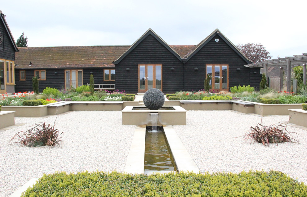 Photo of a contemporary courtyard raised pond in London with a water feature and gravel.
