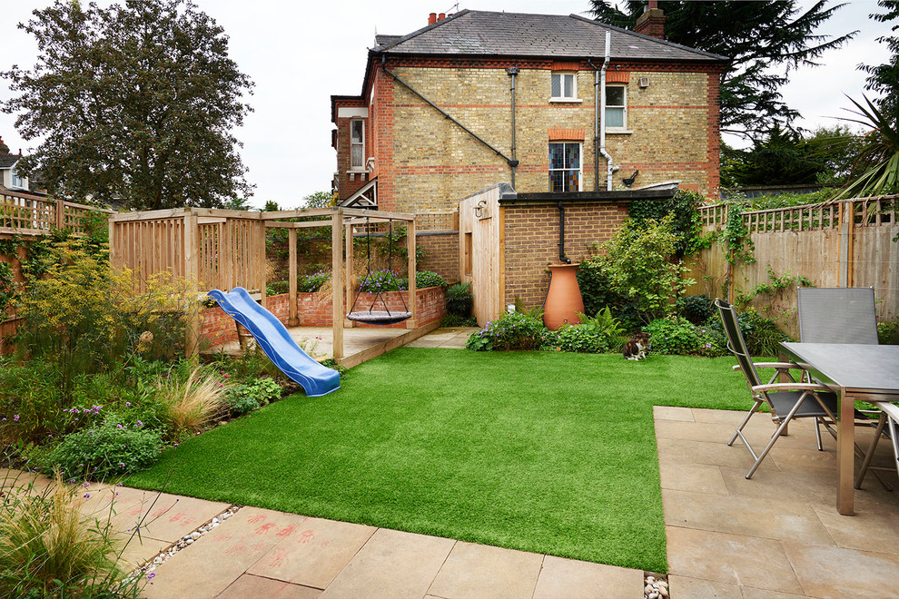 This is an example of a classic back garden in London with a climbing frame and natural stone paving.
