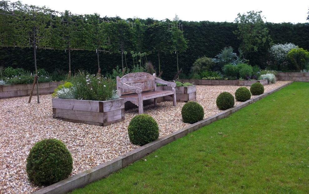 Immagine di un ampio giardino formale contemporaneo esposto in pieno sole dietro casa in estate con un muro di contenimento e ghiaia