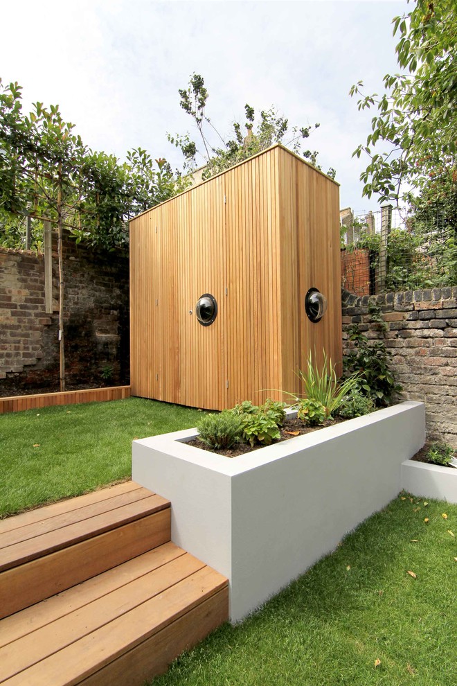 Идея дизайна: регулярный сад среднего размера на заднем дворе в современном стиле с подпорной стенкой и настилом