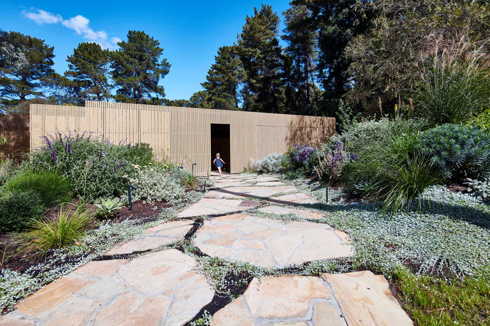 Cette image montre un grand aménagement d'entrée ou allée de jardin design avec une exposition ensoleillée et des pavés en pierre naturelle.
