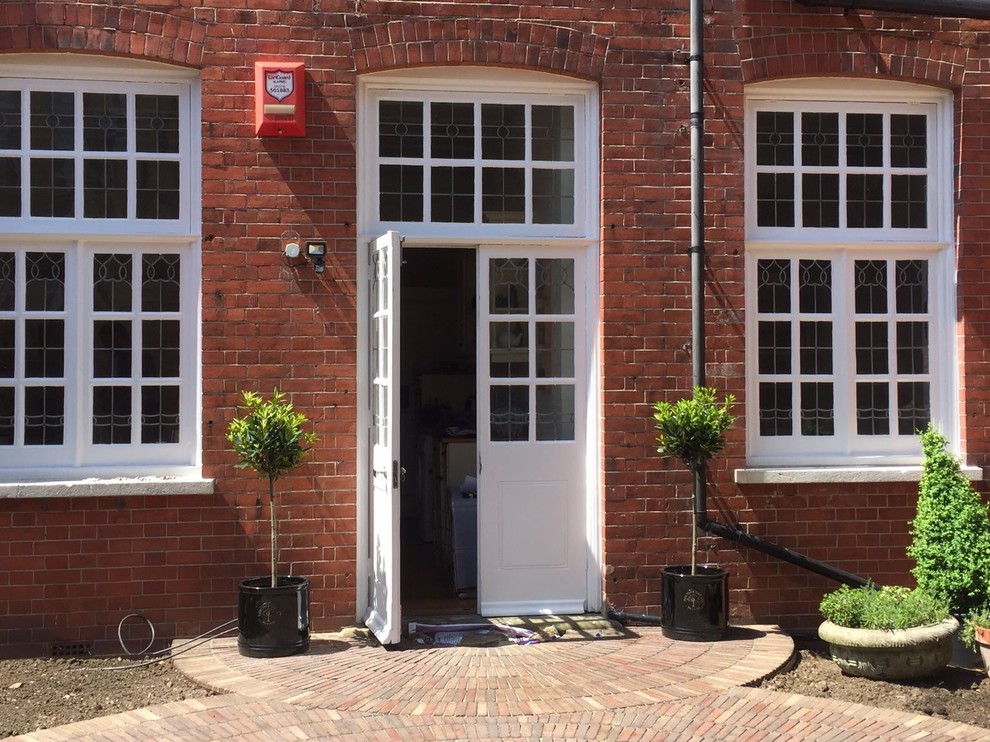 Medium sized traditional courtyard formal full sun garden for summer in Sussex with a potted garden and brick paving.