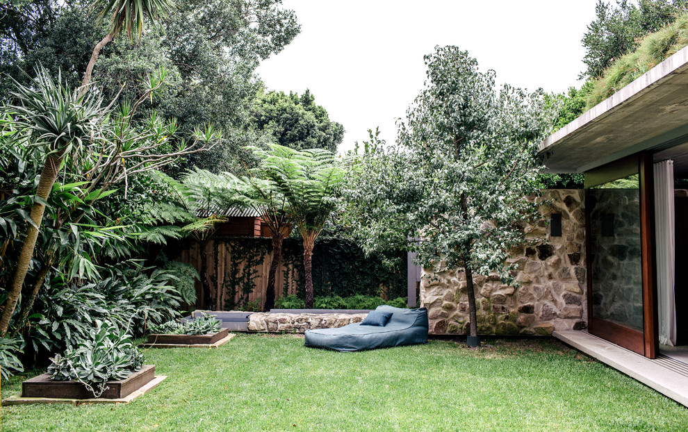 Imagen de jardín actual extra grande en patio trasero con muro de contención y exposición parcial al sol