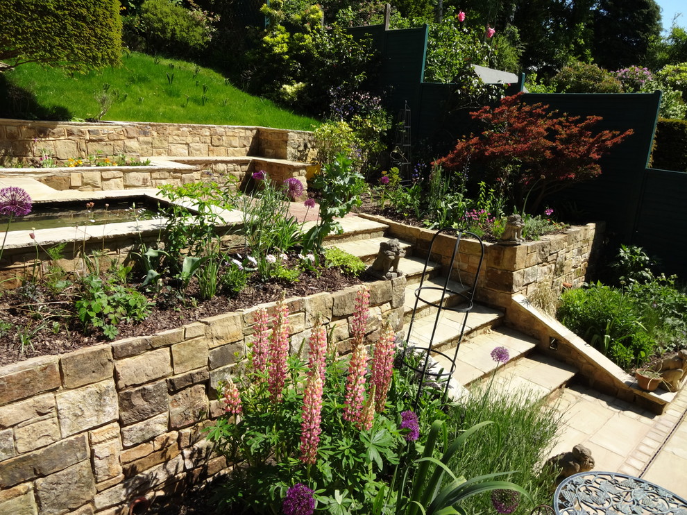 Design ideas for a mid-sized traditional full sun backyard stone formal garden in Sussex for summer.