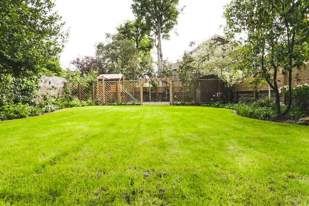 Foto di un giardino formale chic esposto a mezz'ombra di medie dimensioni e dietro casa in estate con uno spazio giochi e pavimentazioni in mattoni