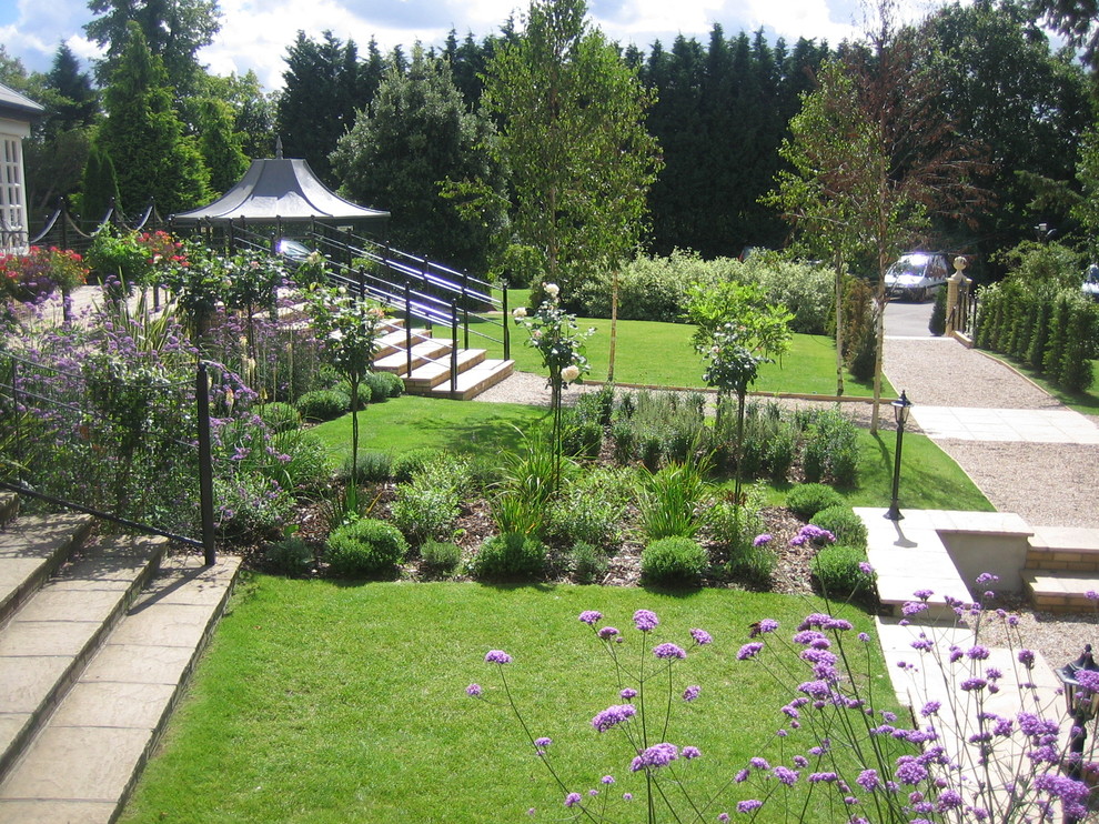 Immagine di un grande giardino formale tradizionale dietro casa con un ingresso o sentiero e ghiaia