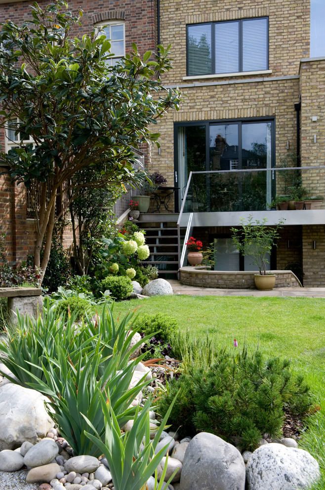 Diseño de jardín tradicional de tamaño medio en verano en patio trasero con jardín francés, exposición parcial al sol y adoquines de piedra natural