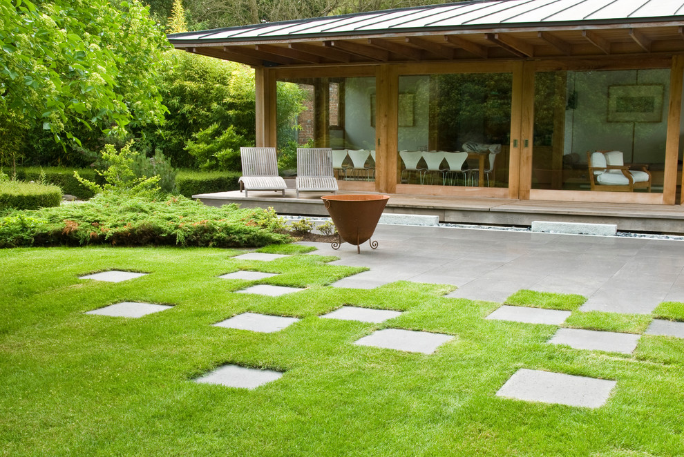 Medium sized world-inspired back partial sun garden for autumn in Sussex with natural stone paving.