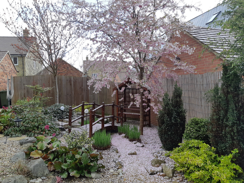 Design ideas for a mid-sized asian rock and full sun backyard river rock landscaping in Oxfordshire.