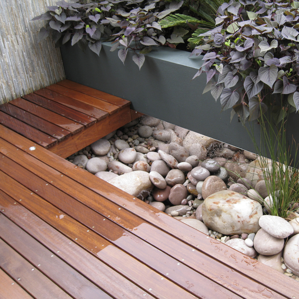 Réalisation d'un petit jardin sur cour design avec un point d'eau et une terrasse en bois.