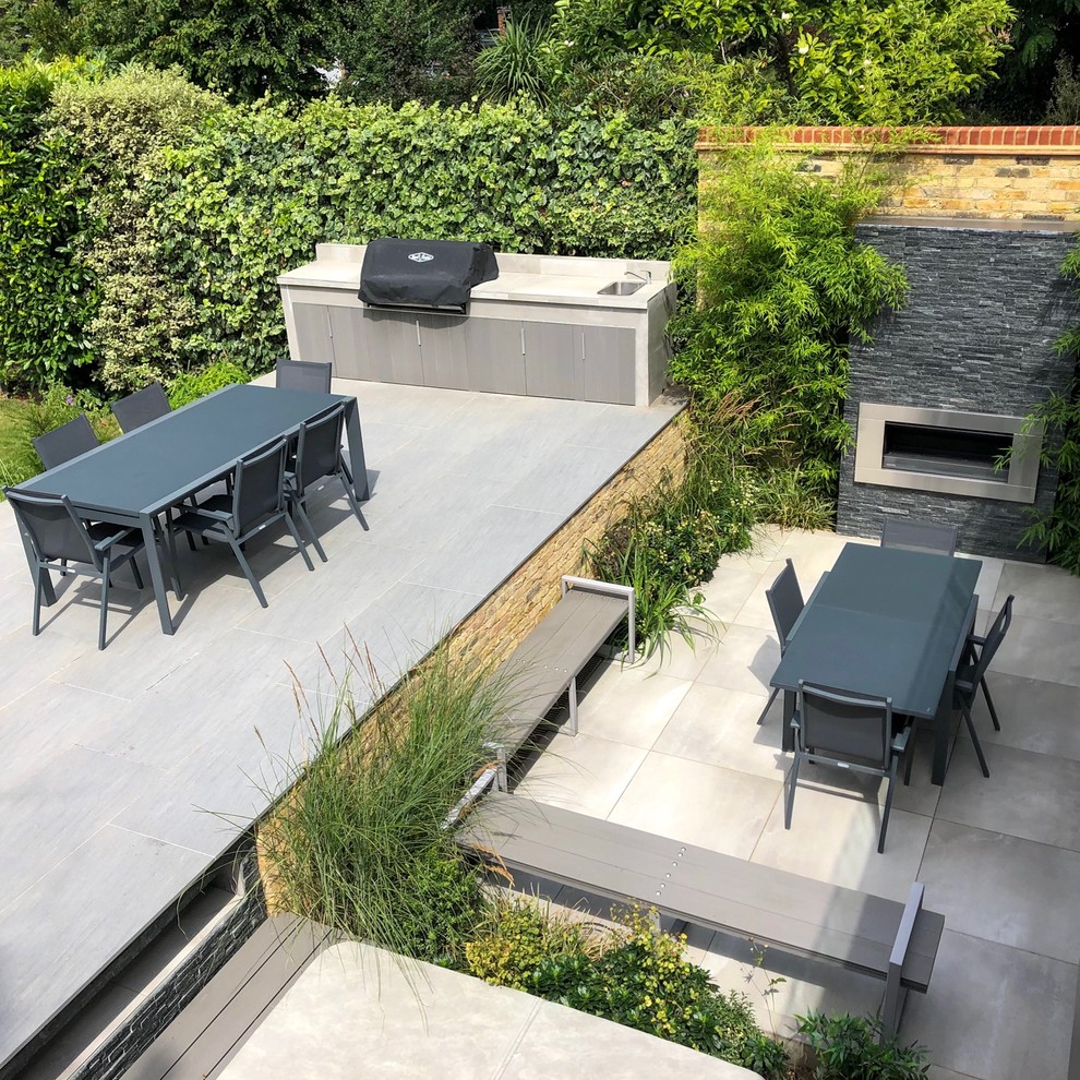 Geometrischer, Mittelgroßer, Halbschattiger Moderner Gartenkamin im Sommer, hinter dem Haus mit Natursteinplatten