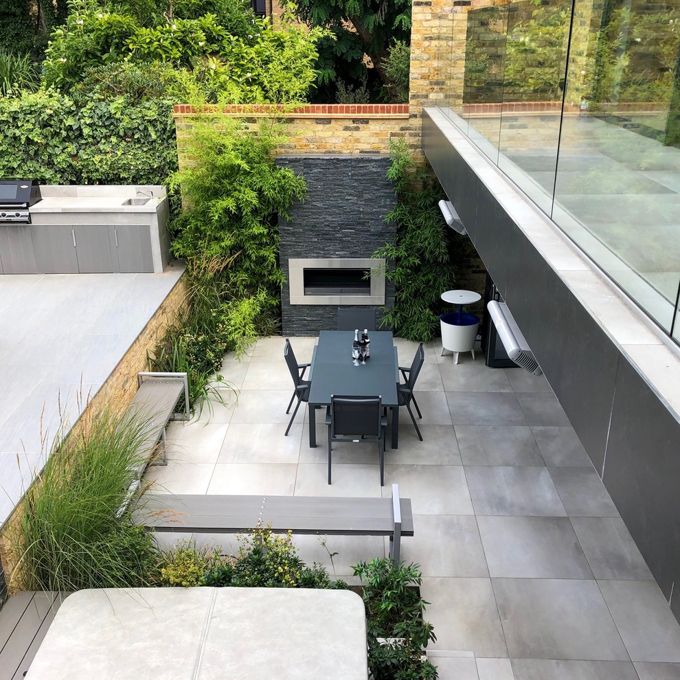 Immagine di un giardino formale minimal esposto a mezz'ombra di medie dimensioni e dietro casa in estate con un caminetto e pavimentazioni in pietra naturale