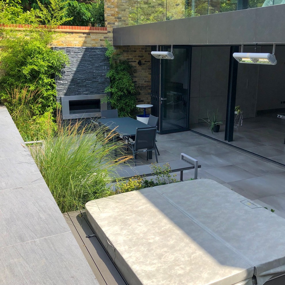 Foto de jardín contemporáneo de tamaño medio en verano en patio trasero con jardín francés, chimenea, exposición parcial al sol y adoquines de piedra natural
