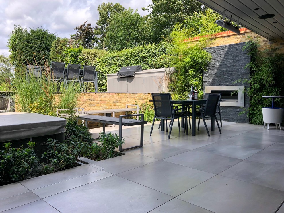 Mittelgroßer Moderner Patio hinter dem Haus mit Kamin und Natursteinplatten in London