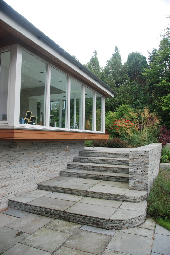 Modelo de jardín de estilo de casa de campo grande en patio lateral con exposición parcial al sol y adoquines de piedra natural