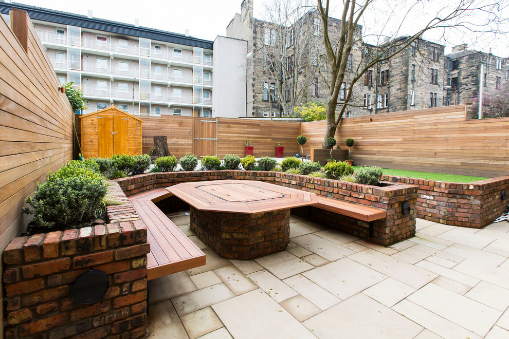 Diseño de jardín actual grande en patio trasero con muro de contención y adoquines de piedra natural
