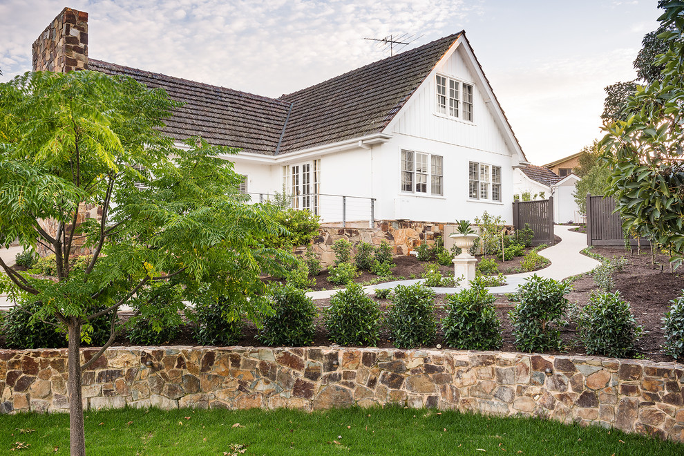 На фото: огромный солнечный, весенний регулярный сад на переднем дворе в классическом стиле с хорошей освещенностью и покрытием из каменной брусчатки с