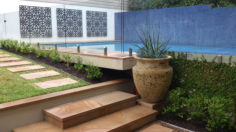 Idee per un giardino moderno dietro casa con un muro di contenimento e pavimentazioni in pietra naturale