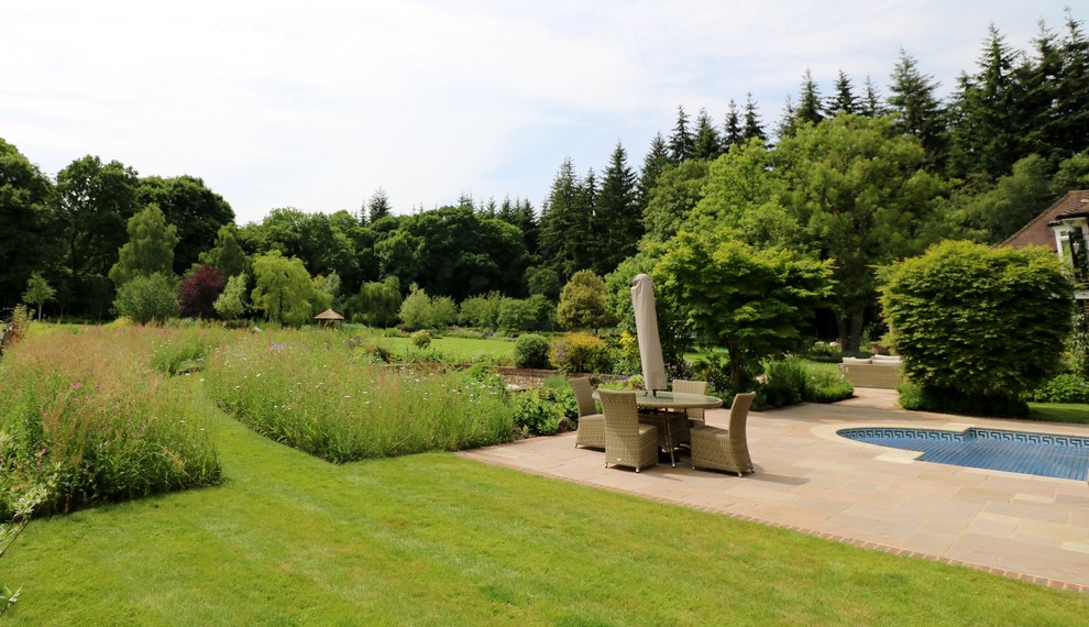 Cette image montre un grand jardin à la française arrière rustique avec une exposition ensoleillée.