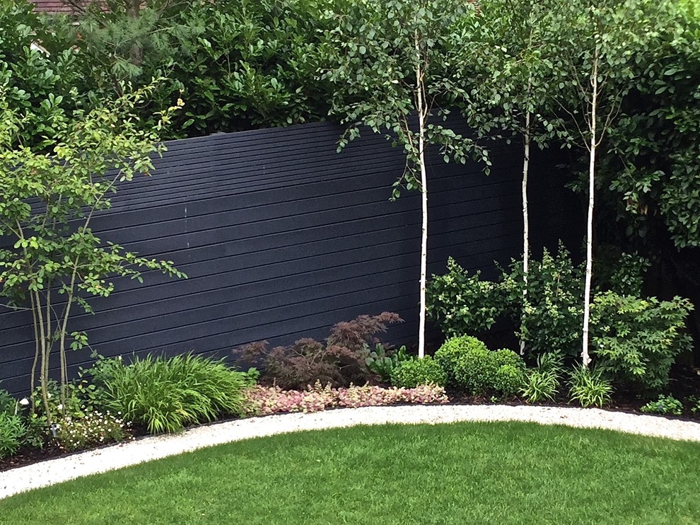 Inspiration for a large contemporary partial sun backyard stone landscaping in London for summer.