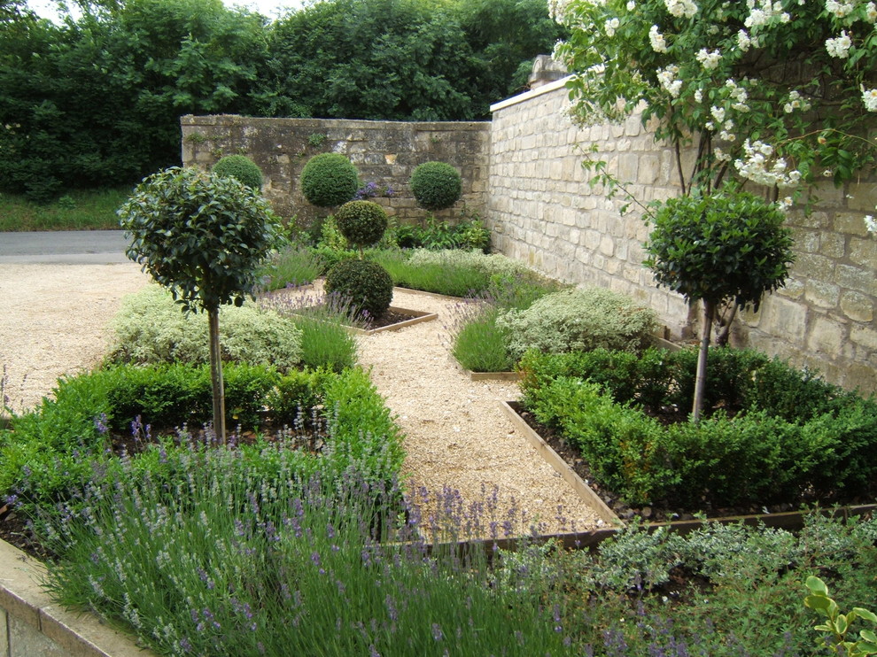 Cette image montre un petit jardin à la française avant rustique avec une exposition ensoleillée et du gravier.