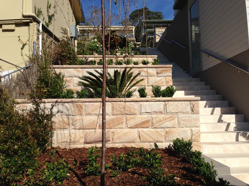 This is an example of a traditional sloped garden in Sydney with a garden path and natural stone paving.