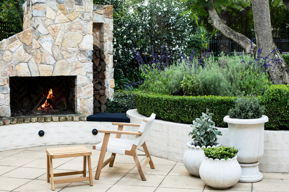 Photo of a small traditional courtyard formal full sun garden for winter in Sydney with a fireplace and natural stone paving.