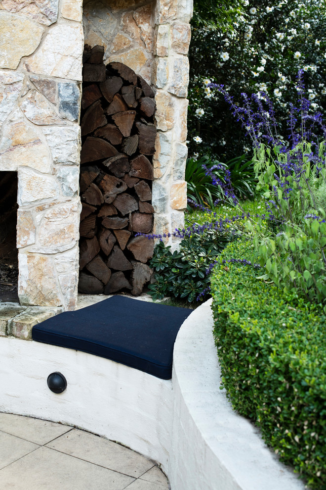 Small classic courtyard formal full sun garden for winter in Sydney with a fireplace and natural stone paving.