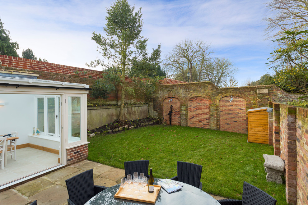 Geometrische, Kleine Urige Gartenmauer im Sommer, hinter dem Haus mit direkter Sonneneinstrahlung und Pflastersteinen in Kent