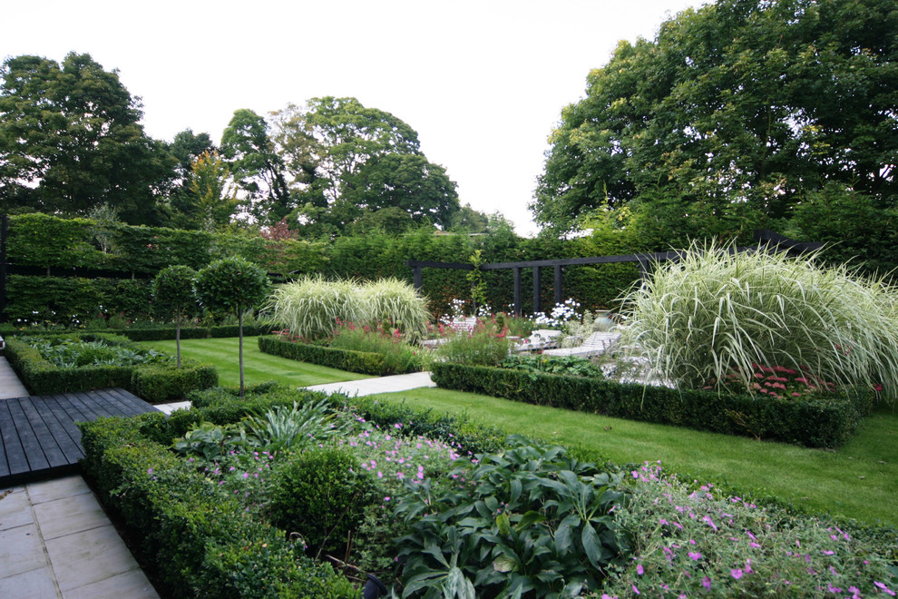 This is an example of a large traditional back formal garden in Berkshire with natural stone paving.