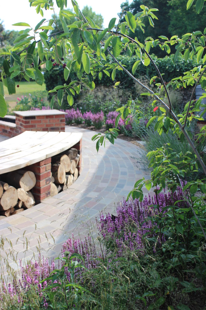 Idées déco pour un jardin arrière classique de taille moyenne avec une exposition ensoleillée et des pavés en brique.