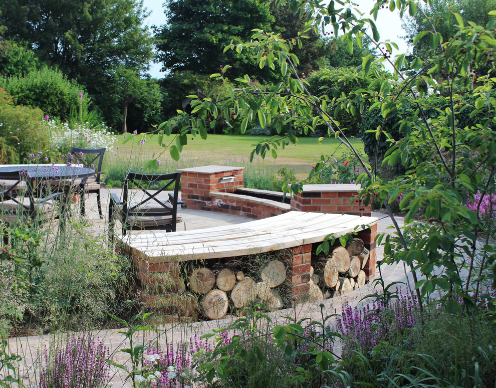 Modelo de jardín de tamaño medio en patio trasero con jardín francés, muro de contención y adoquines de piedra natural