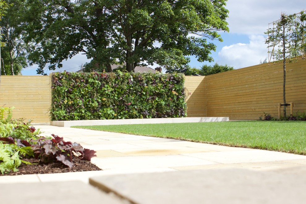 Cette photo montre un grand jardin arrière tendance l'été avec une exposition ensoleillée, des pavés en pierre naturelle et une clôture en bois.