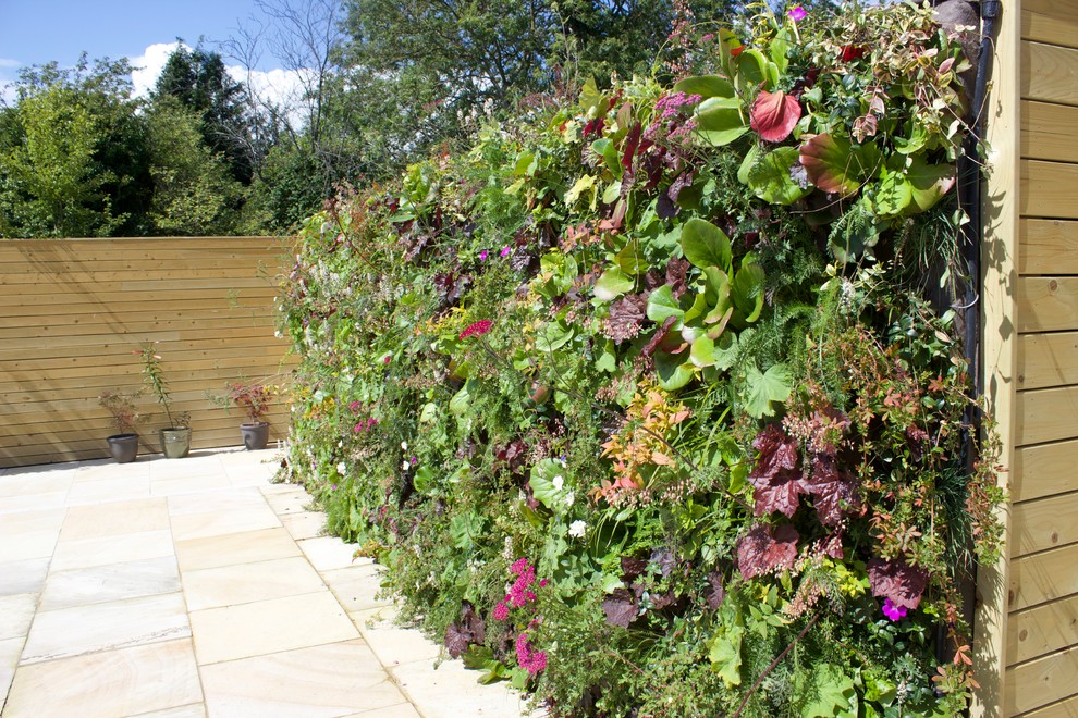 Esempio di un grande giardino formale design esposto in pieno sole dietro casa in estate con pavimentazioni in pietra naturale e recinzione in legno