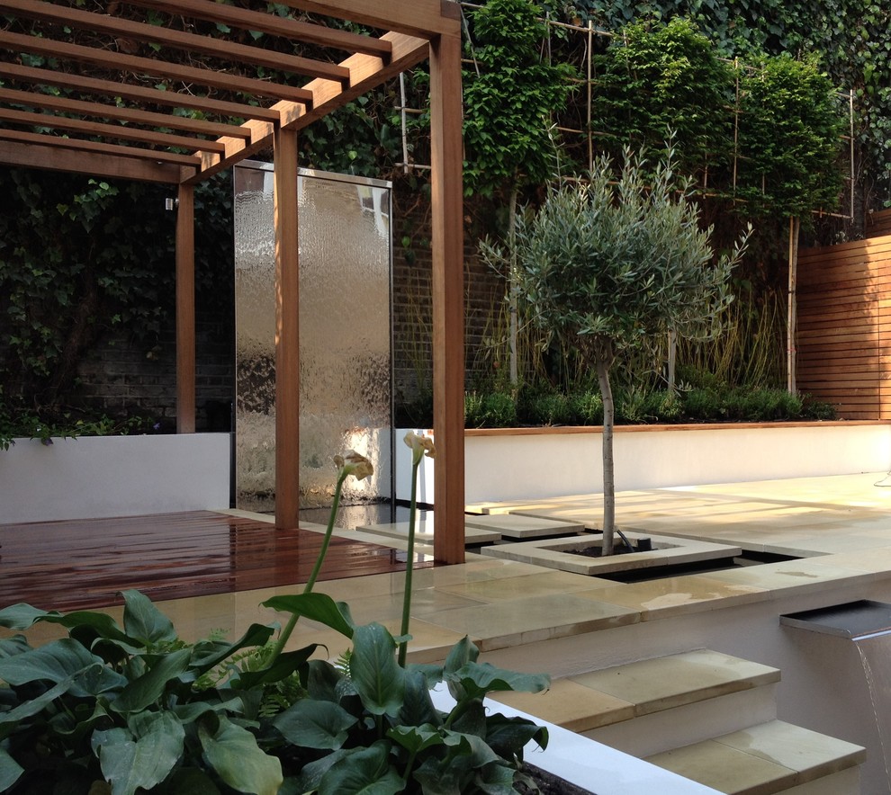 Photo of a small contemporary back partial sun garden for summer in London with a water feature and natural stone paving.