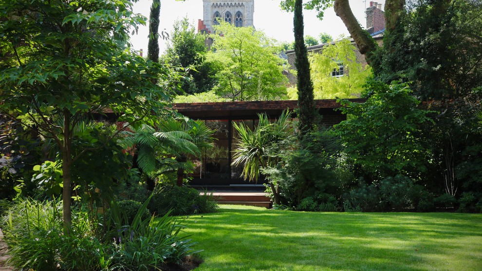 Réalisation d'un grand jardin arrière ethnique avec une exposition partiellement ombragée et une terrasse en bois.