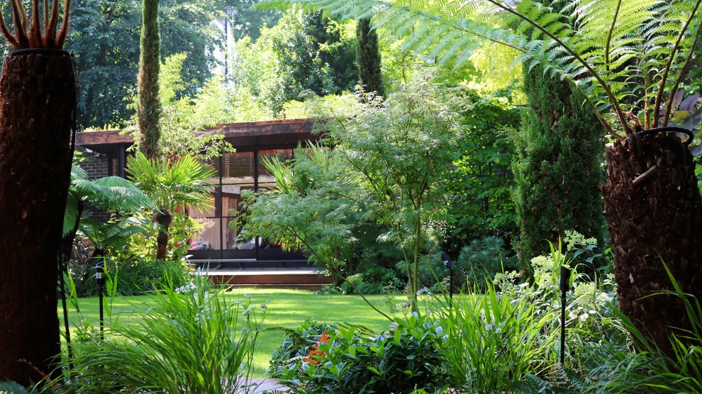 Immagine di un grande giardino tropicale esposto a mezz'ombra dietro casa con pedane