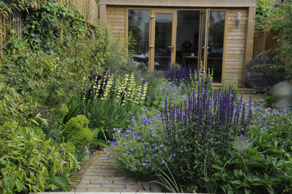 Photo of a small contemporary partial sun backyard brick landscaping in London.