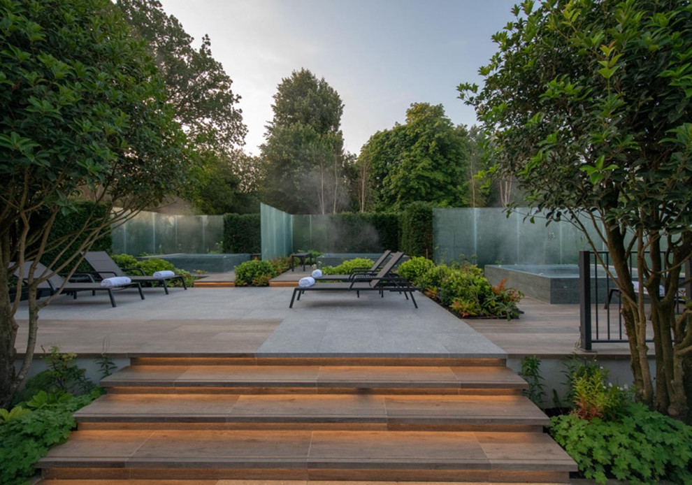 Immagine di un grande giardino design esposto in pieno sole nel cortile laterale in primavera con pavimentazioni in pietra naturale