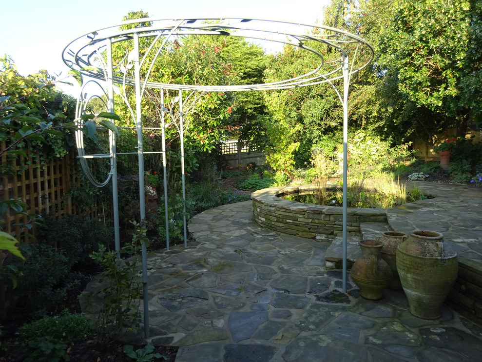 Mittelgroßer, Halbschattiger Retro Gartenteich hinter dem Haus mit Natursteinplatten in Kent