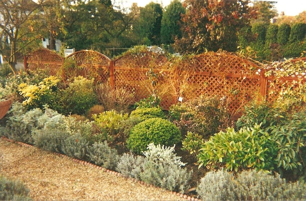 Foto på en funkis trädgård i delvis sol framför huset