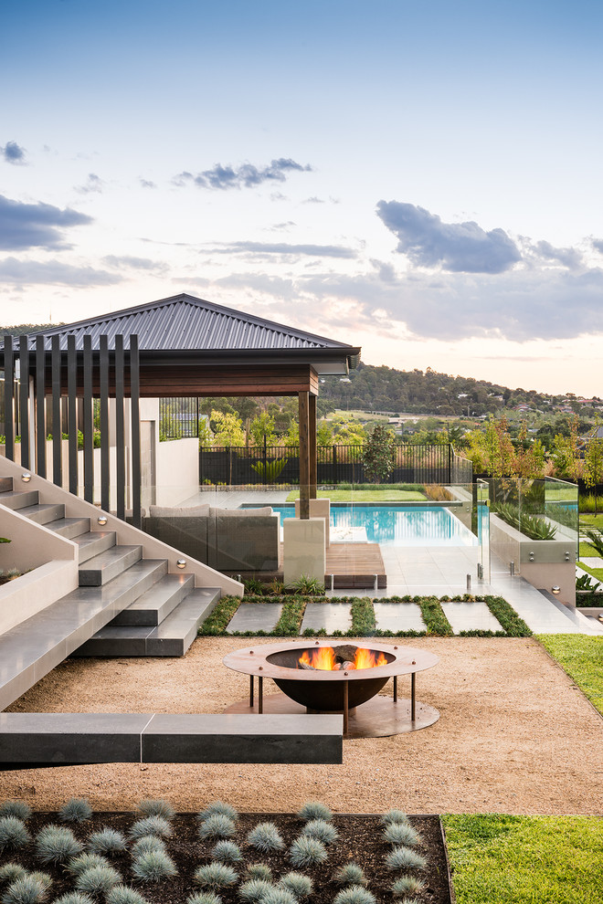 Foto di un grande giardino minimal esposto in pieno sole dietro casa con un focolare e ghiaia